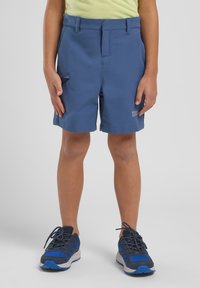 Pantalones cortos azules hechos de una tela ligera, con bolsillos laterales y una textura suave. Combinados con zapatillas deportivas azules y grises.