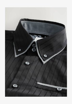 Camisa de rayas negras con cuello de patrón contrastante, botones grises y bolsillo. Tela suave con diseño estructurado y acabado a medida.