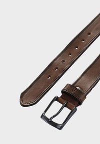 Ceinture en cuir marron avec une boucle en métal noir mat, des coutures le long des bords et plusieurs trous pour un ajustement.