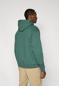 Πράσινο φούτερ με κουκούλα από μαλακό ύφασμα, με κορδόνι στην κουκούλα, ριμπ μανσέτες και λογότυπο στο μανίκι. Άνετη εφαρμογή και λεία υφή.