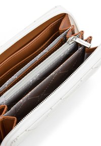Portafoglio in pelle marrone con un'esterno bianco. Presenta più scomparti, comprese sezioni con zip e aperte. Interno foderato con motivi.