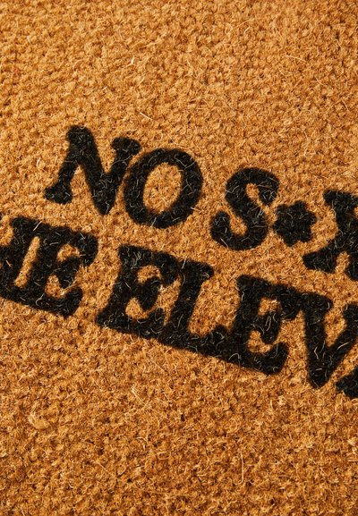 Brūns kokosšķiedras durvju paklājs ar teksturētu virsmu. Centrā redzams melns uzraksts "NEKĀDAS SEKSA LIFĀ".