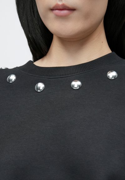 Čierna mikina s rebrovaným výstrihom, s lesklými striebornými okrúhlymi nitmi pozdĺž goliera, vyznačujúca sa hladkou textúrou.