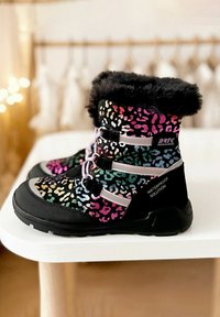 Wasserdichte Stiefel mit schwarzem Grund, verziert mit einem bunten Leopardenmuster. Weicher Kunstfellbund, kontrastierende Schnürsenkel und rutschfeste Gummisohle.
