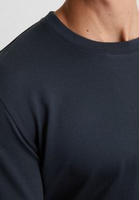 Donker marineblauwe, lichte stoffen t-shirt met een ronde hals en ribbelstructuur, met schone naden en een nauwsluitende pasvorm.