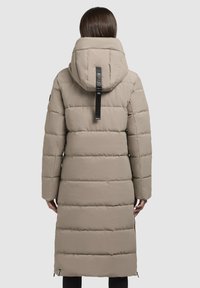 Beige lang, puffy jakke med hætte, vandret syninger og et mærke på bagsiden. Lynlåse ved kanten. Glat tekstur.