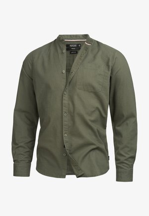 Zielona koszula z mieszanki lnu z kołnierzykiem mandarńskim, zapięciem na guziki z przodu i kieszenią na piersi po lewej stronie. Posiada subtelną fakturę i długie rękawy.