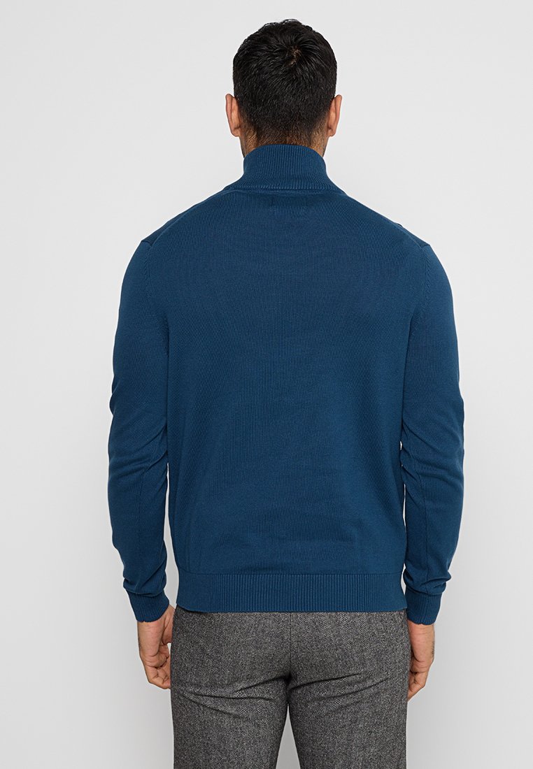Granatowy sweter z teksturowanej tkaniny, z wysokim kołnierzem, prążkowanymi mankietami i dołem, prezentujący dopasowany krój i gładki materiał.