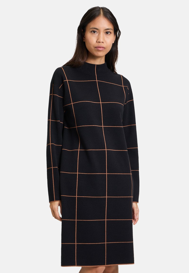 Svart långärmad klänning med figursydd passform, prydd med ett rutmönster i orange. Tillverkad av ett mjukt tyg med hög hals.