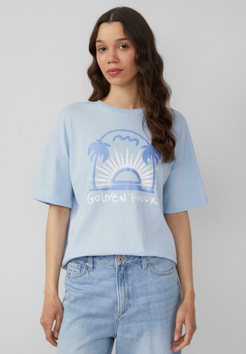 Lichtblauw T-shirt met korte mouwen, voorzien van een grafische afbeelding van palmbomen, een zon en de tekst "Golden Hour" in wit en donkerder blauw.