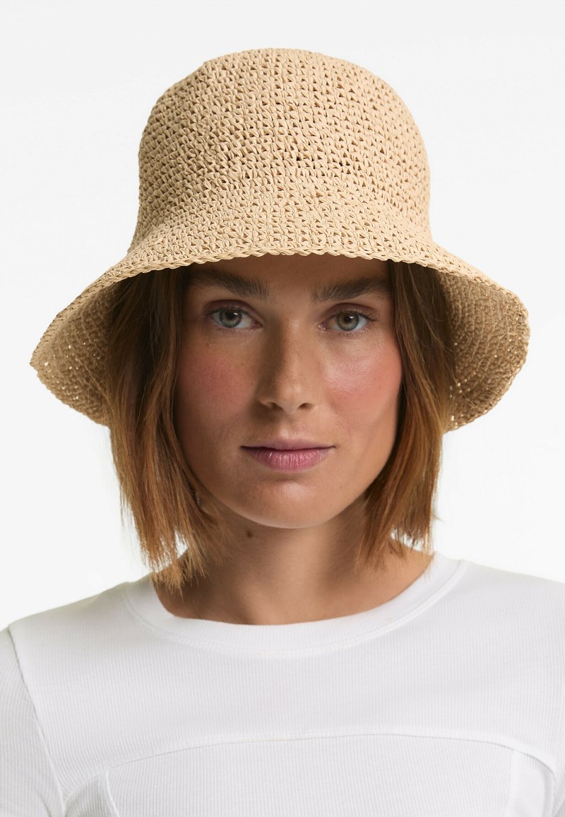 Woven straw bucket hat in light tan with a wide, floppy brim and a textured design, providing a casual, breathable style.
