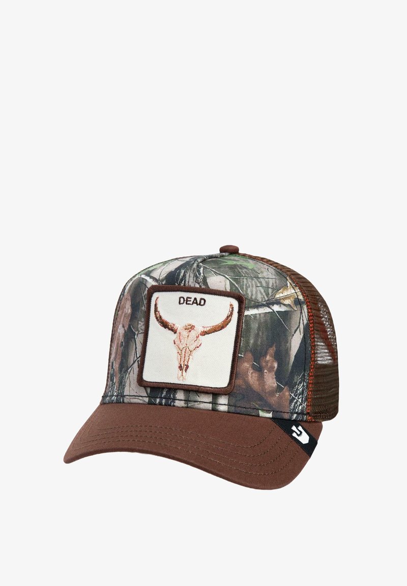 Camo trucker cap with brown brim. Features a beige patch with a skull graphic and "DEAD" text, outlined in dark brown. Mesh sides.
