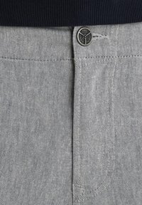 Pantalones de mezclilla gris con una cinturilla acanalada en azul marino y cierre de botón plateado. Incluye bolsillos delanteros con ligera textura.