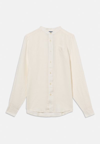 Langärmliges cremefarbenes Hemd mit Stehkragen, Knopfleiste vorne und einer einzelnen Brusttasche, flach auf weißem Hintergrund liegend.