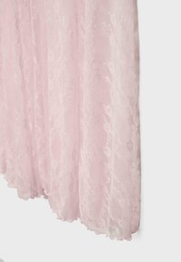 Tissu en dentelle rose clair avec motifs floraux et bords festonnés, suspendu avec des plis doux sur un fond uni.