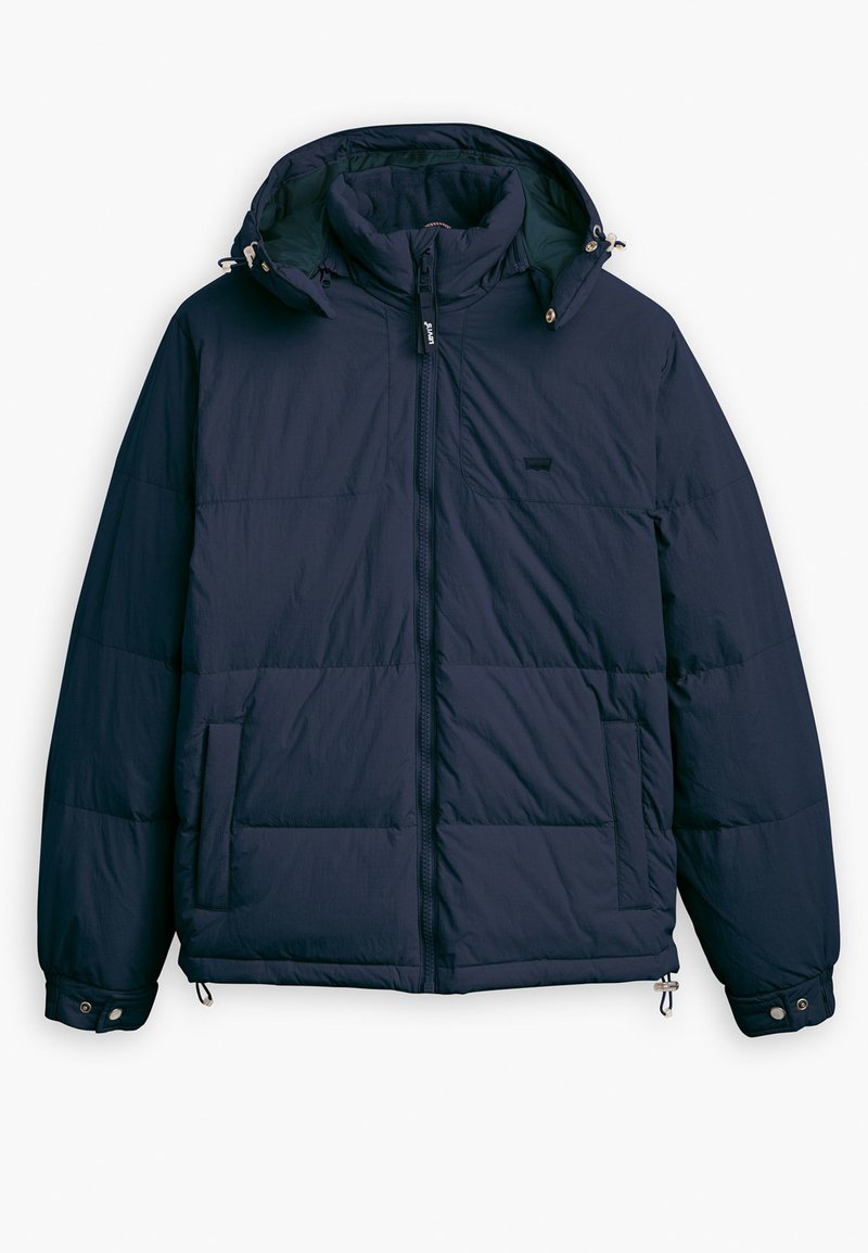 Chaqueta acolchada azul marino con cierre de cremallera, capucha ajustable, bolsillos laterales y puños elásticos. Textura suave y diseño acolchado.
