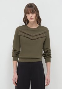 Felpa verde oliva con colletto a girocollo, maniche lunghe e dettagli a frange sovrapposte in un motivo a zigzag sul petto.