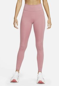Rosa högmidjade leggings i ett mjukt, stretchigt material. Har en sömlös midja och en figurnära silhuett. Bärs med vita sneakers.