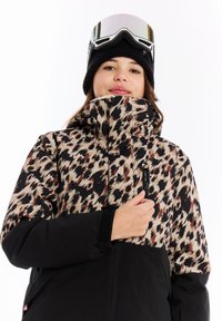 Skijack met een gemusterde bovenkant in zwart, beige en bruin, met een effen zwarte onderkant en een ritszak.