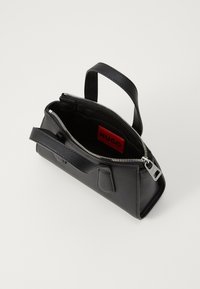 Black leather handbag with textured surface, zip closure, and a short handle. Inside features a red brand label. Compact rectangular shape.