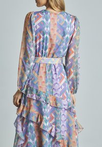 Langärmliges Kleid aus durchscheinendem Stoff mit lebhaften geometrischen Mustern in Lila, Orange und Grün. Rüschensaum und taillierte Details.