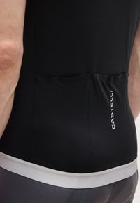 Vista posteriore di una persona che indossa una maglia da ciclismo nera con tre tasche posteriori e il logo bianco "Castelli" sulla tasca destra.