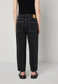 Zwarte high-waisted jeans met een rechte pijp, achterzakken, zichtbare stiksels en een leren label op de tailleband.