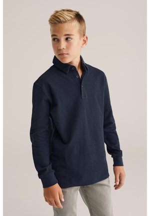 Marinblå långärmad polotröja med krage, tvåknappsslutning och ribbad textur, tillsammans med ljusgrå byxor.