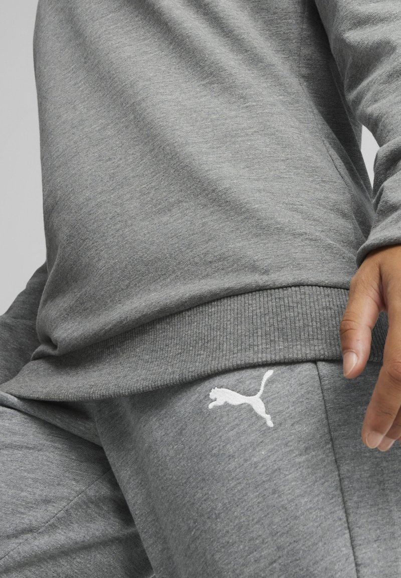 Felpa grigia e pantaloni della tuta realizzati in tessuto morbido, con polsini a coste e un accento del logo bianco sull'anca. Texture liscia in tutto il capo.