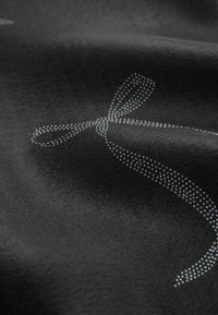 Juodas audinys su tekstūrizuota paviršiumi, kuriame pavaizduota taškuota balta lankelė. Medžiaga atrodo lygi, su nedideliu blizgesiu.