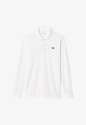 Vit långärmad polotröja i bomullsblandning med knäppkrage och en liten grön krokodil-logotyp på vänster bröst.