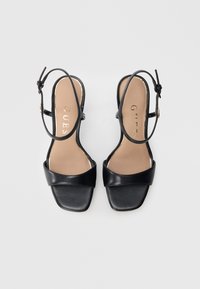 Sandali con tacco in pelle nera con design a punta quadrata, ampia fascia anteriore, sottile cinturino alla caviglia e logo metallico sulla soletta.