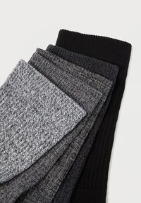 Τέσσερις ζευγάρια πλεκτών κάλτσων σε διάφορες αποχρώσεις του γκρι και του μαύρου. Υφή με ραμφωτά επάνω μέρη και συνδυασμένο πλεκτό σχέδιο.