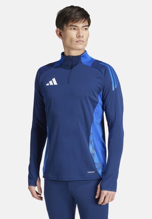 Navy sporttop met lange mouwen en blauwe accenten, hals met halve rits en Adidas-logo. Glad textuur met een grafisch patroon aan de zijkant.