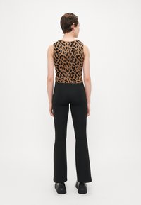 Brune og sorte dyreprint crop top, parret med helt sorte flarebukser, båret med sorte platåsko.