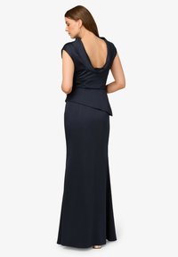 Tmavě modré saténové večerní šaty s hlubokým vykrojením na zádech, krátkými rukávy a přiléhavým střihem se rozšířeným spodním lemem. Hladká textura po celé délce.