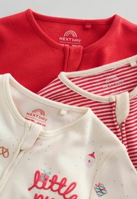 Set aus drei Babybekleidungsstücken: eines in einfarbigem Rot, eines in Creme mit festlichem Druck und eines mit roten Streifen. Alle haben einen runden Ausschnitt und Logotags.