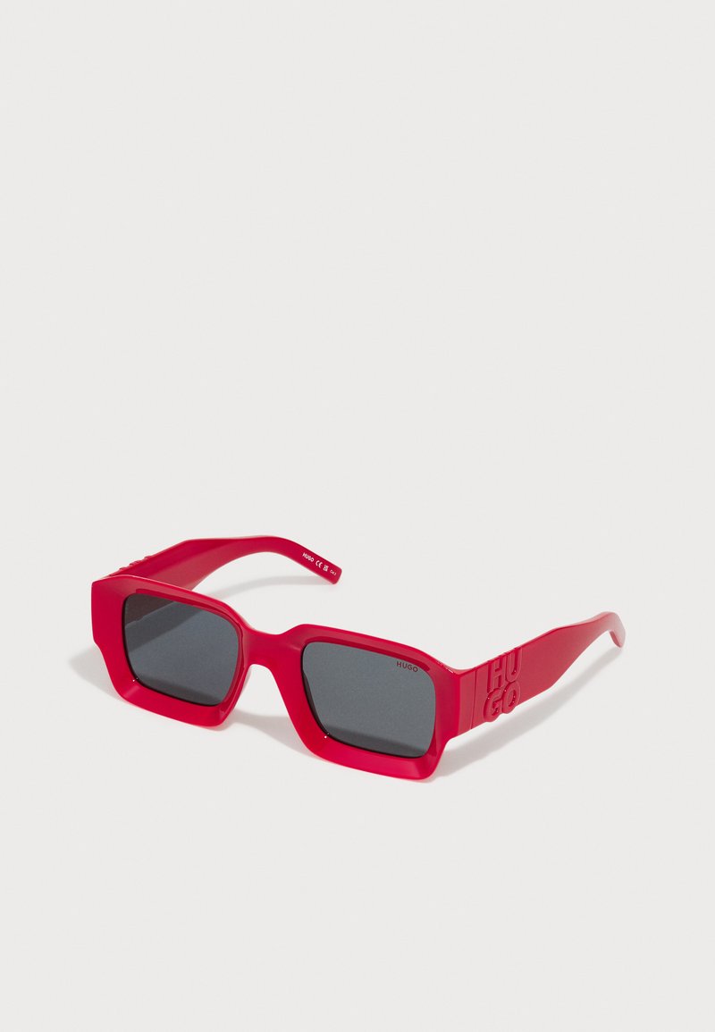 Red rectangular sunglasses with dark lenses and "HUGO" embossed on the temple, set against a plain white background.