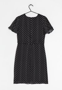 Svart klänning med korta volangärmar, prydd med vita prickar och vertikala ränder, avslutad med en dragkedja bak.