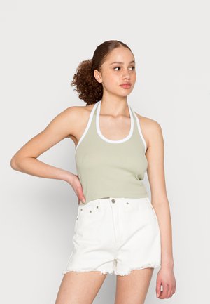 Top halter verde claro com uma textura canelada, apresentando detalhes em branco. Combinado com calções de ganga brancos de cintura alta, desfiados na bainha.