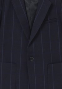 Marynarka w kolorze granatowym wykonana z fakturowanej tkaniny z niebieską kratką. Posiada dwie przednie kieszenie, zapięcie na jeden guzik oraz satynową podszewkę.