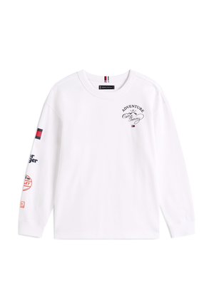 T-shirt blanc à manches longues avec un col rond, arborant des graphiques imprimés sur la poitrine et les manches, incluant divers logos et accents.