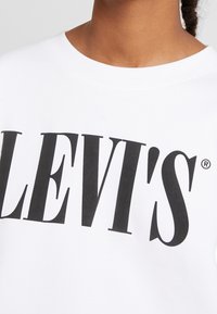 Bílá mikina s výrazným černým logem Levi's, kulatým výstřihem a měkkou texturou. Vyrobena strojově s standardním střihem.