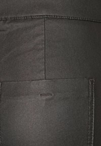 Svarta denimbyxor med en texturerad yta, med en bakficka och kontrasterande sömmar längs sömmarna. Enkelt och funktionellt design.