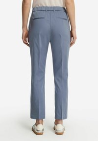 Ljusblå byxor med resårmidja och rak passform, försedd med två bakfickor och en slät, mjuk tygtextur.