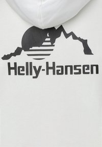 Sweat à capuche blanc présentant un graphisme noir de montagnes et de soleil avec le texte "Helly-Hansen" en dessous, mettant en avant des formes géométriques et un contraste de couleurs.