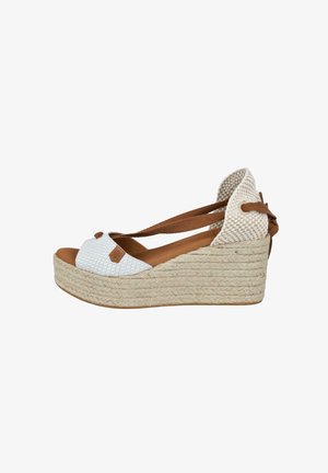 Sandalia tipo cuña espadrille con plataforma de yute tejido, tira frontal blanca texturizada y lazo marrón para atar en el tobillo.