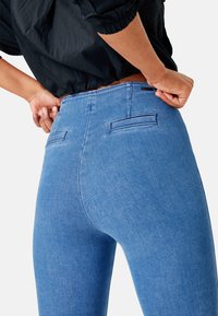 Blauwe denim jeans met een getailleerd ontwerp, voorzien van achterzakken, een middelhoge taille en subtiele stikseldetails op de naden.