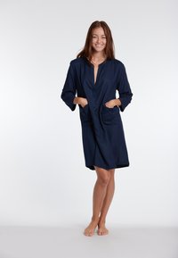 Abito blu navy con scollatura a V, maniche a tre quarti e due tasche frontali. Tessuto liscio e design fino al ginocchio.