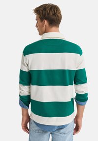 Groene en witte gestreepte langemouwen polo met een kraag, casual pasvorm en opgerolde mouwen over een denim shirt.